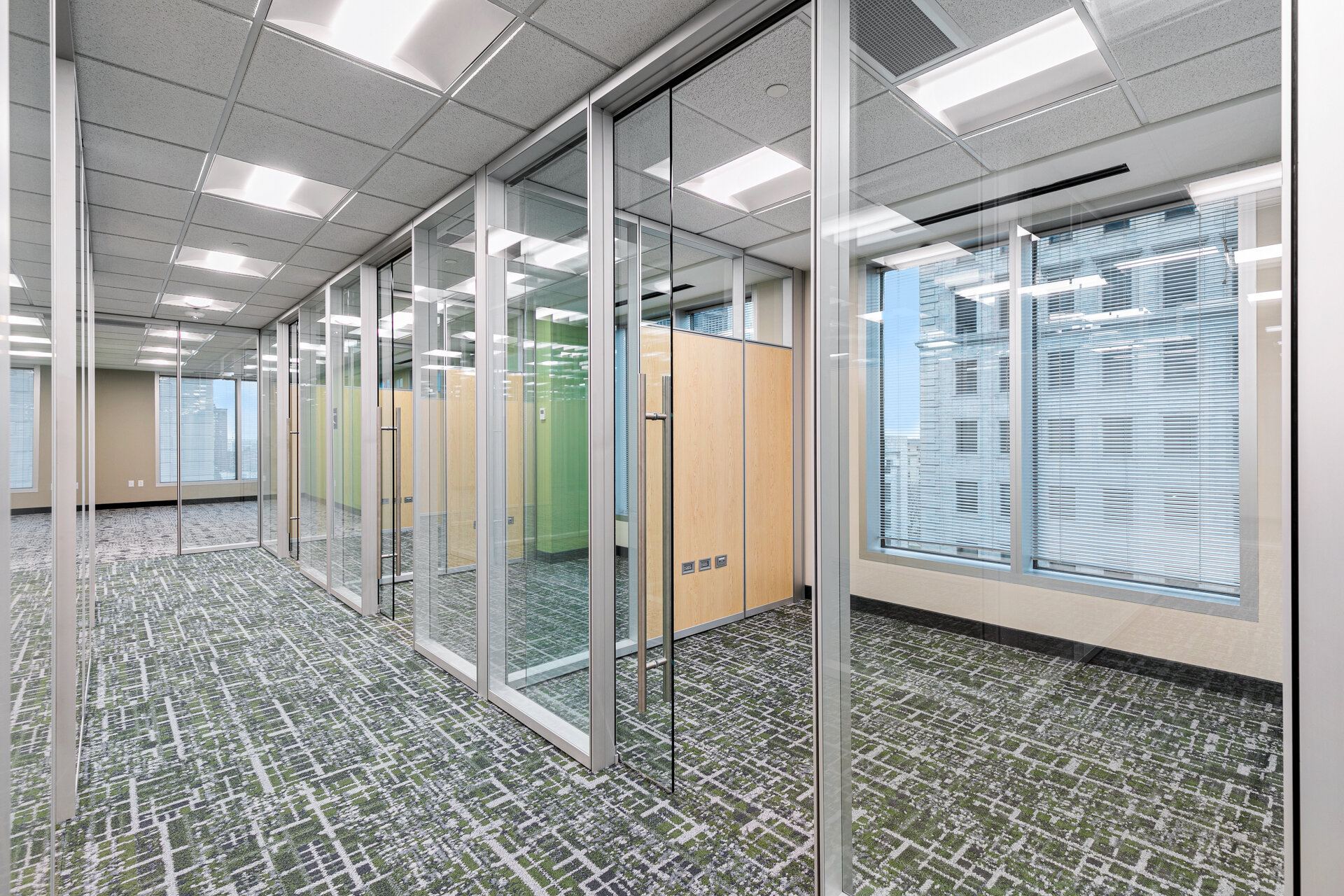 Glass-walled offices with city views and modern furnishings in high-rise commercial build-out — Skoda Construction, Northeast Ohio
