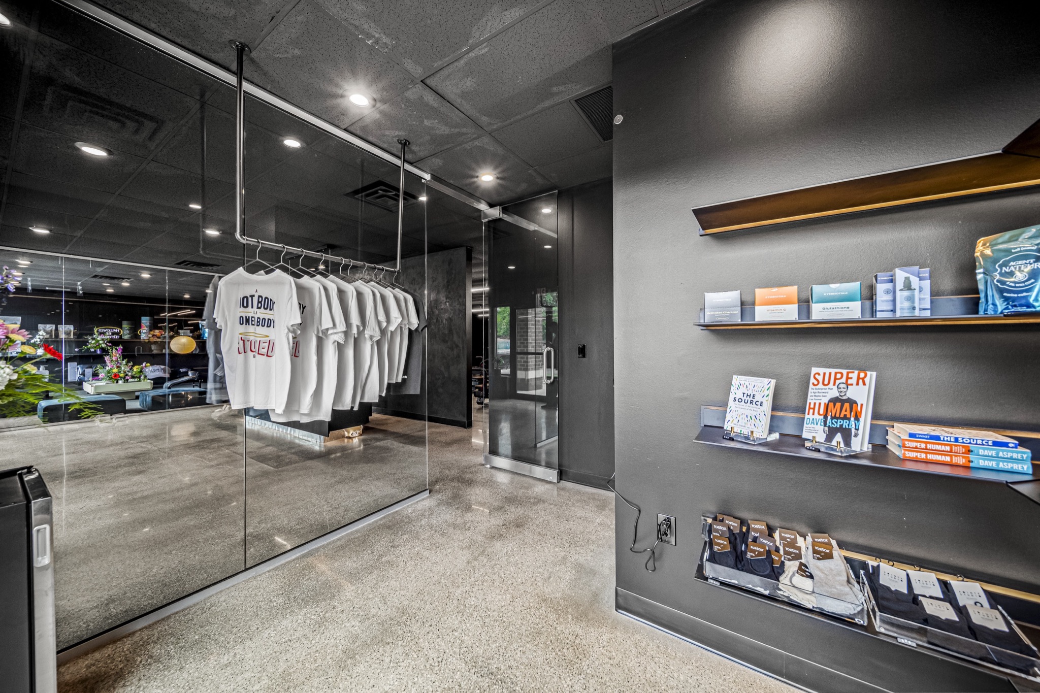 Boutique fitness retail display with branded merchandise, glass walls, and floating shelves — commercial construction by Skoda Construction, Northeast Ohio