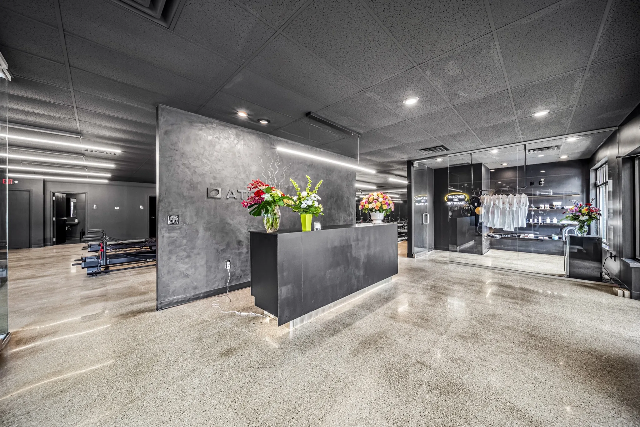 Industrial-modern reception desk with concrete accent wall and polished floors in premium fitness studio — commercial build-out by Skoda Construction, Northeast Ohio
