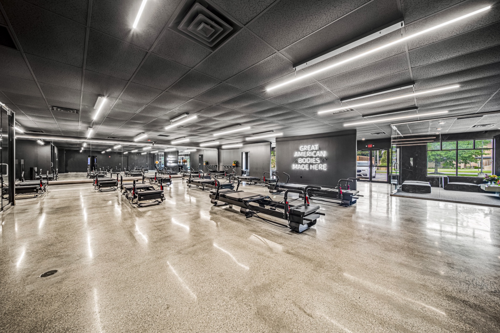 Open-plan fitness studio with reformer machines and illuminated motivational signage — commercial construction by Skoda Construction, Northeast Ohio