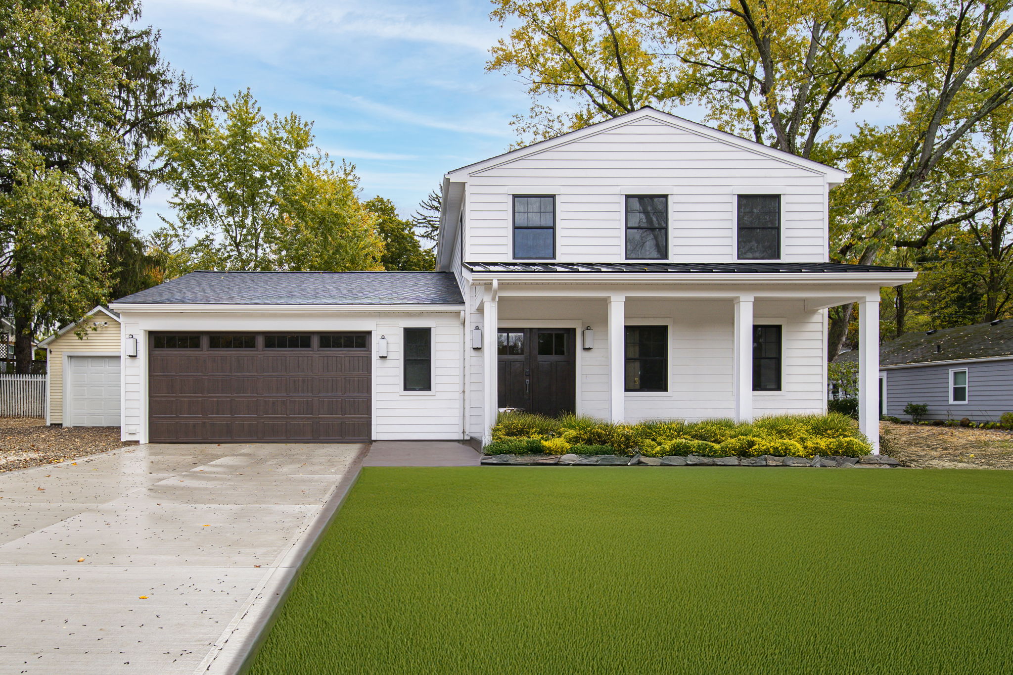 White modern farmhouse with dark wood garage door and covered porch — new construction by Skoda Construction, Northeast Ohio