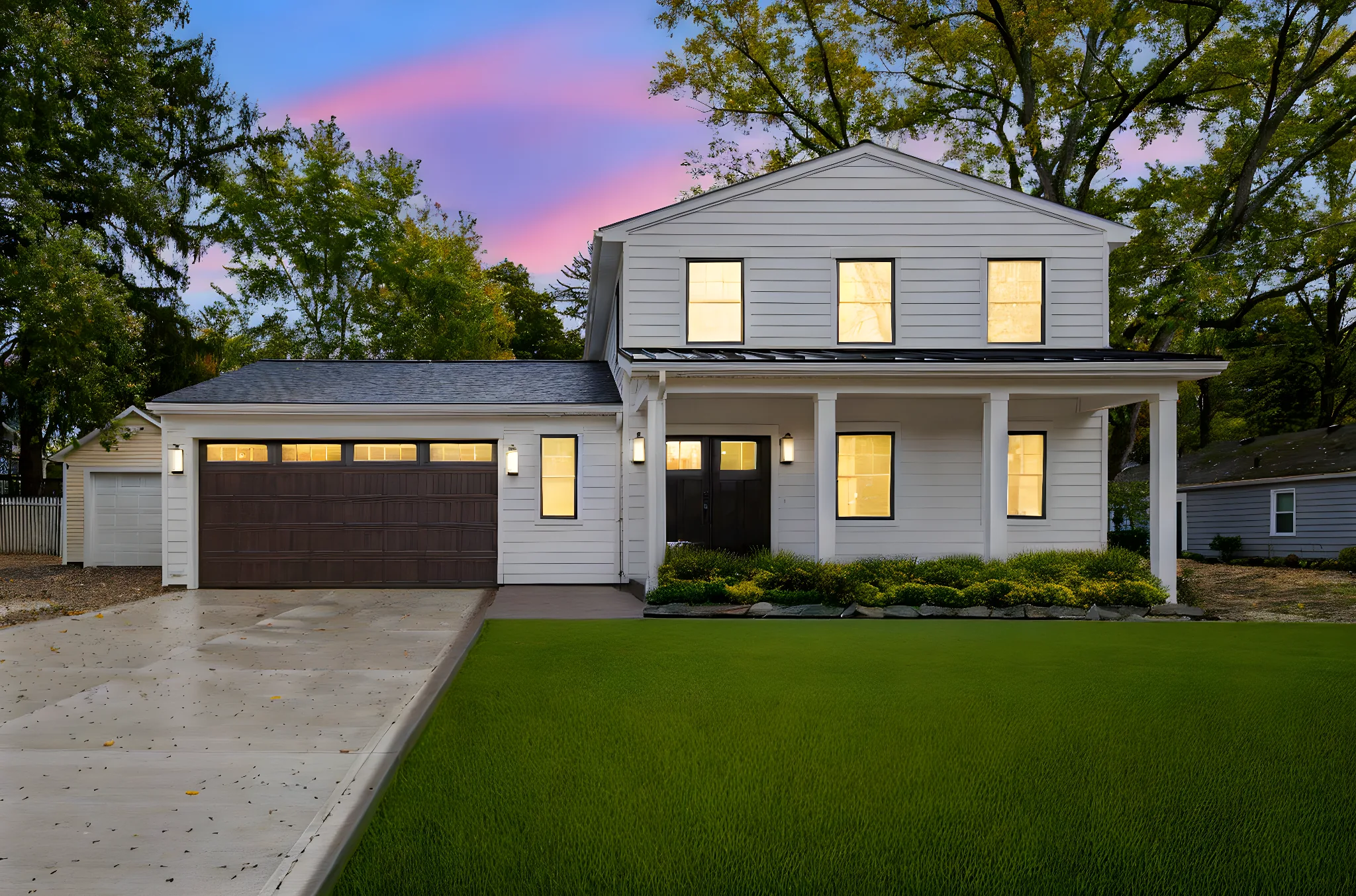 Modern farmhouse at twilight with glowing interior lights and sunset sky — custom home by Skoda Construction, Northeast Ohio