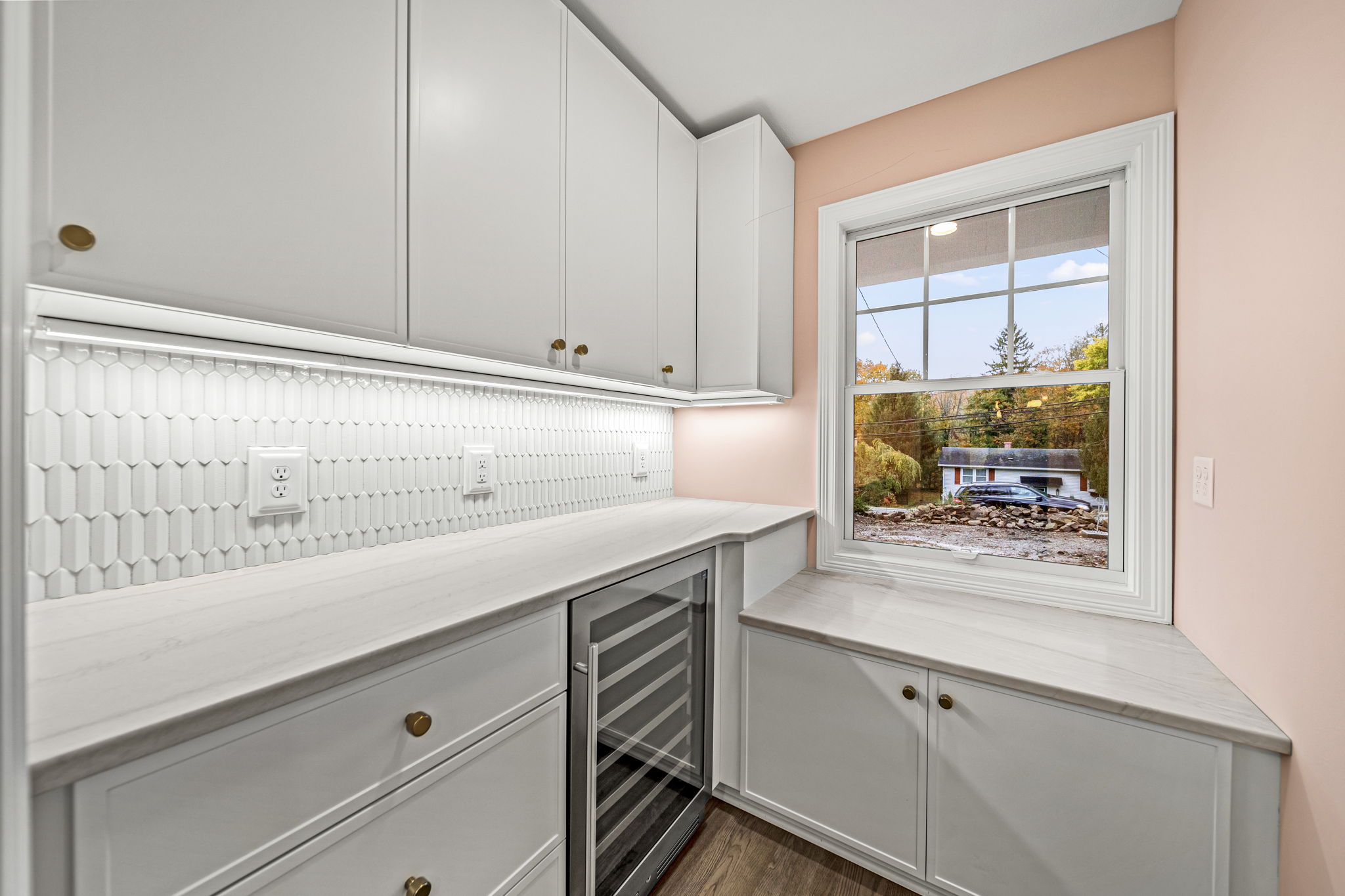 Butler's pantry with wine refrigerator, geometric tile backsplash, and brass hardware — modern farmhouse by Skoda Construction
