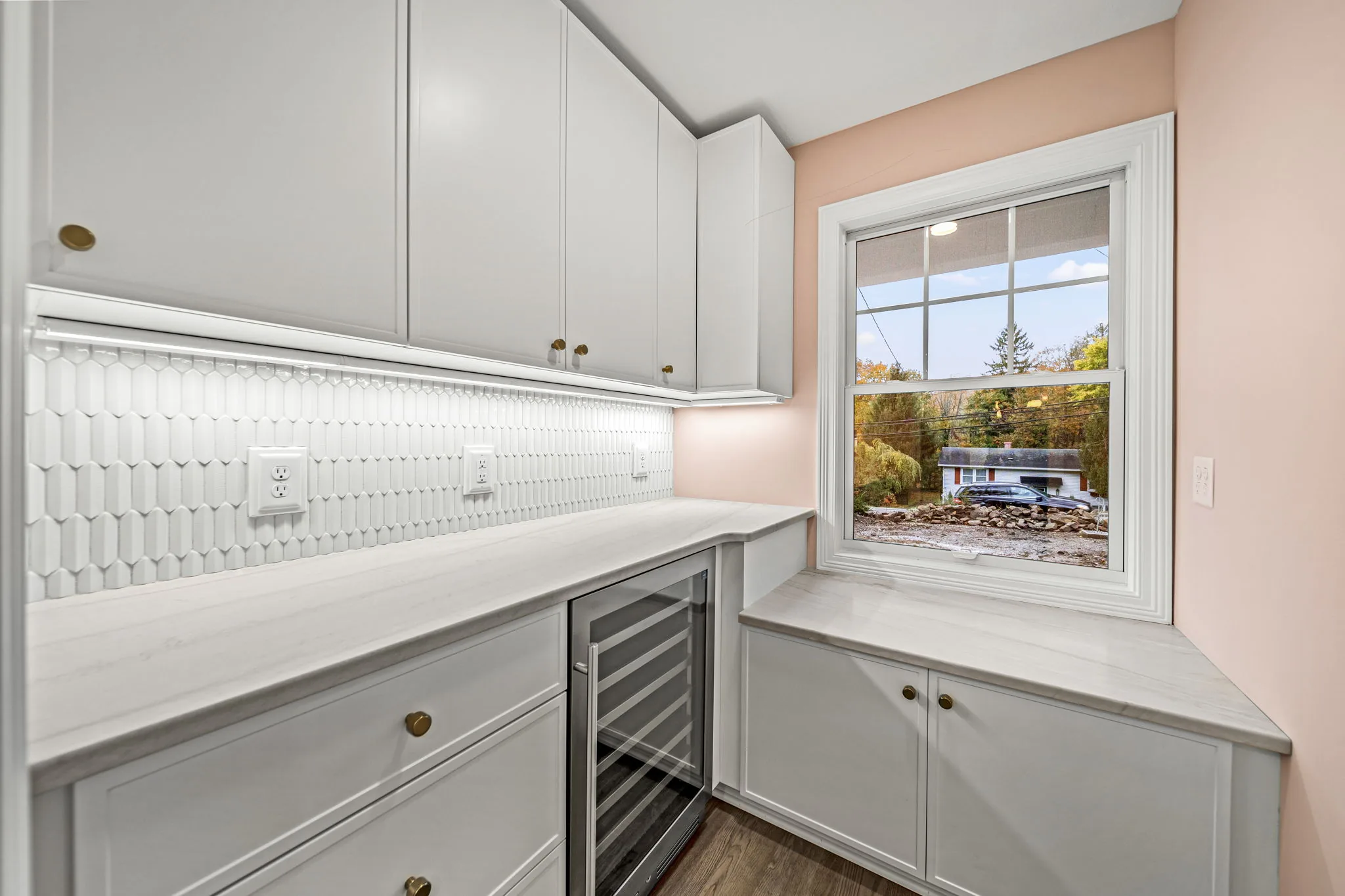 Butler's pantry with wine refrigerator, geometric tile backsplash, and brass hardware — modern farmhouse by Skoda Construction