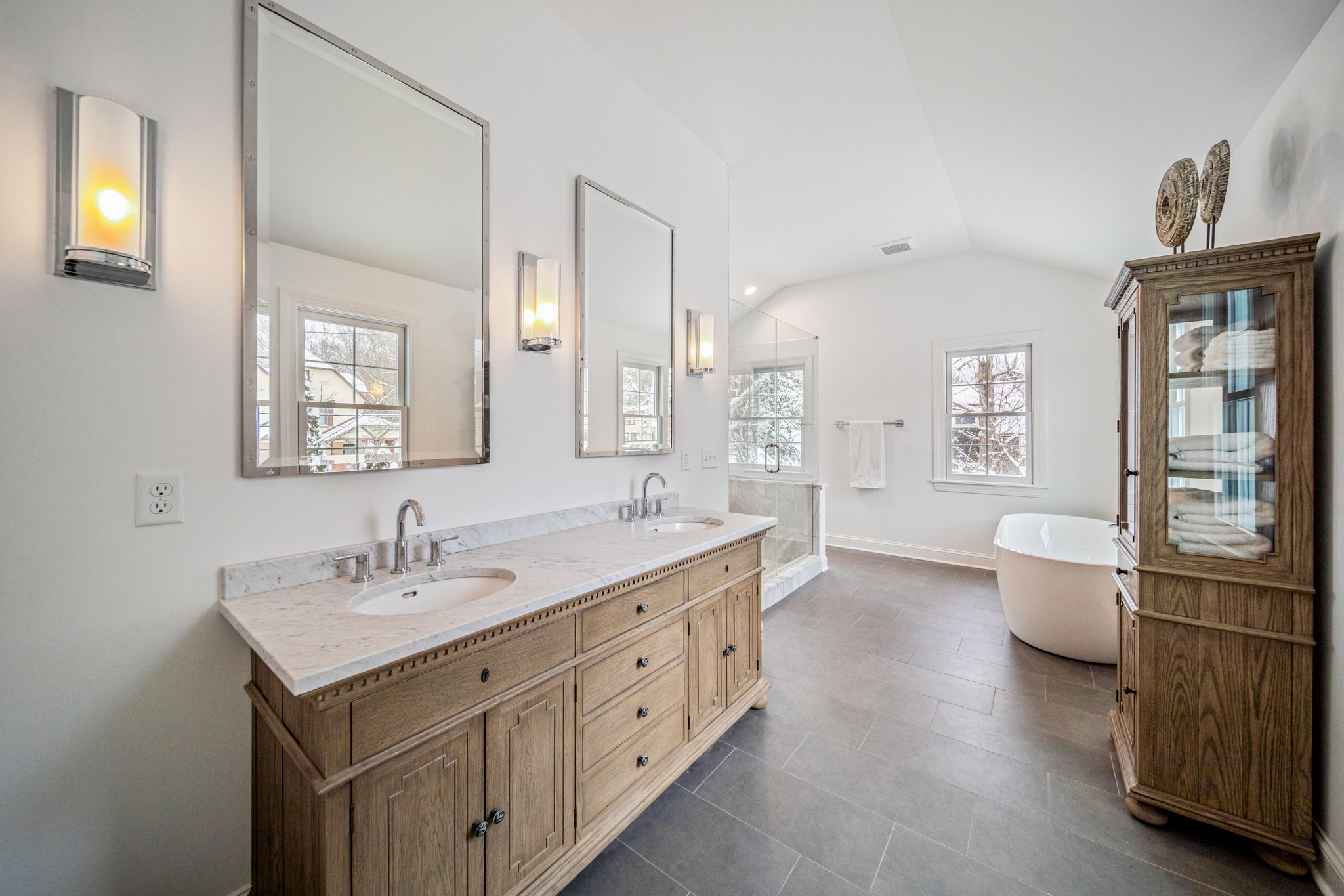 Spacious master bathroom with double vanity, marble countertops, freestanding tub, and modern sconces — luxury bath renovation by Skoda Construction, Northeast Ohio