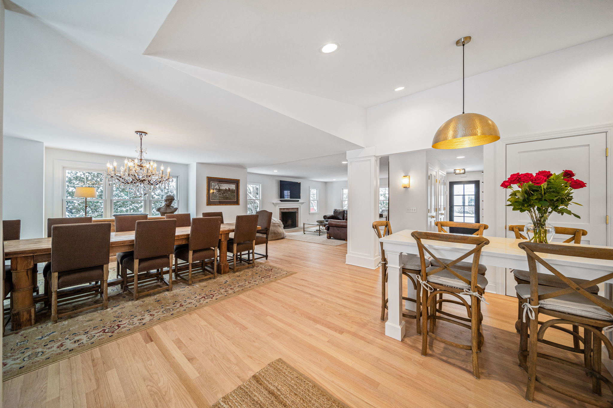 Open-concept dining and kitchen with gold dome pendant lights, crystal chandelier, and hardwood floors — luxury renovation by Skoda Construction, Northeast Ohio