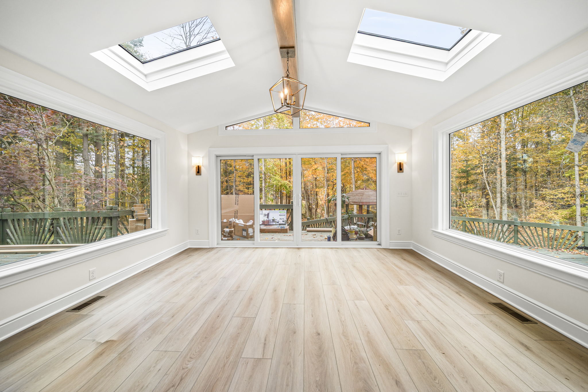 Four-season sunroom with cathedral ceiling, dual skylights, and panoramic autumn woodland views — custom home by Skoda Construction, Northeast Ohio
