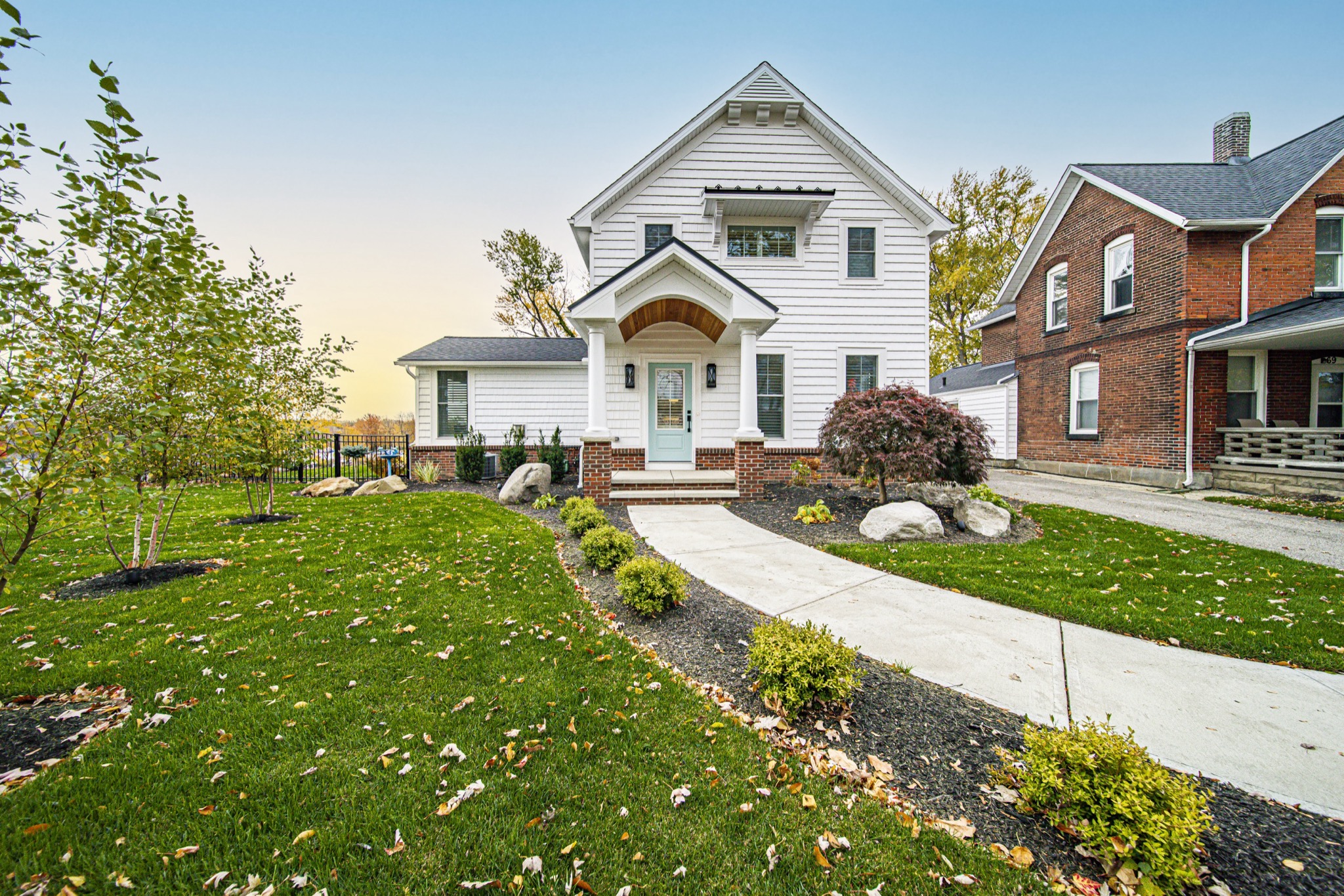 Custom white farmhouse front elevation with arched portico entry and professional landscaping — luxury home by Skoda Construction, Northeast Ohio