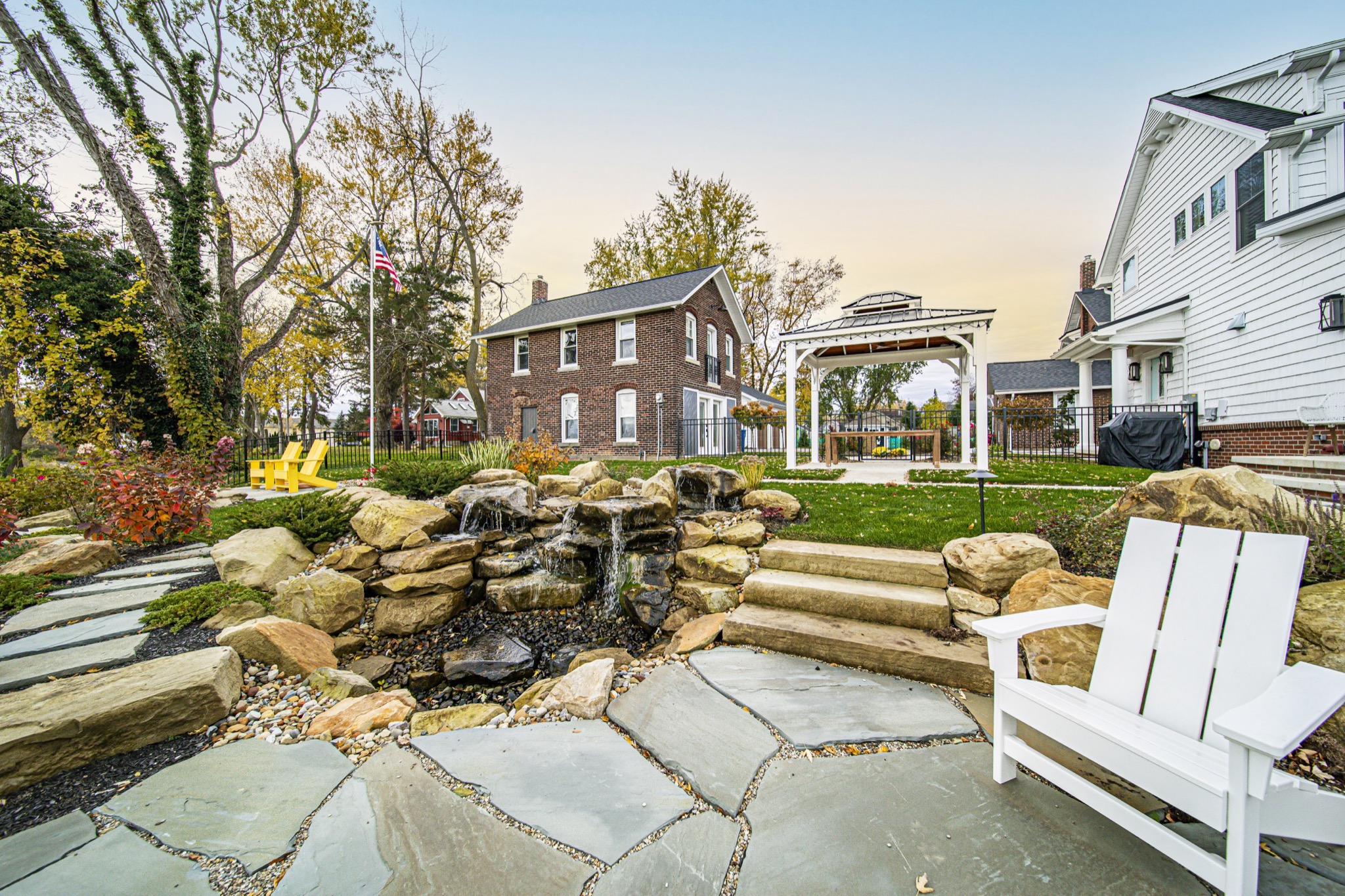 Natural stone waterfall and flagstone patio with Adirondack seating in custom backyard — luxury outdoor living by Skoda Construction, Northeast Ohio