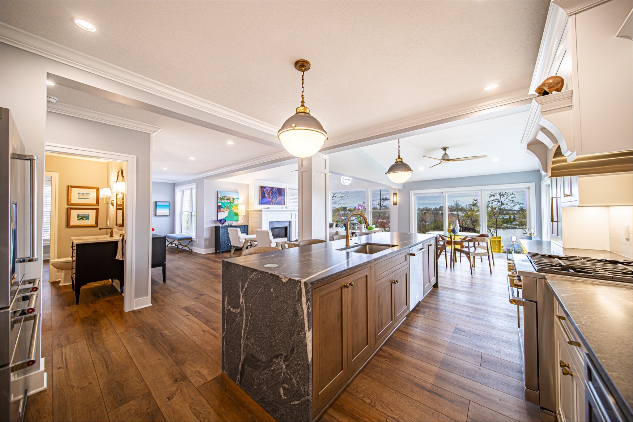 Craftsman kitchen with dark marble waterfall island, brass globe pendants, and wide-plank hardwood floors — custom home by Skoda Construction, Northeast Ohio