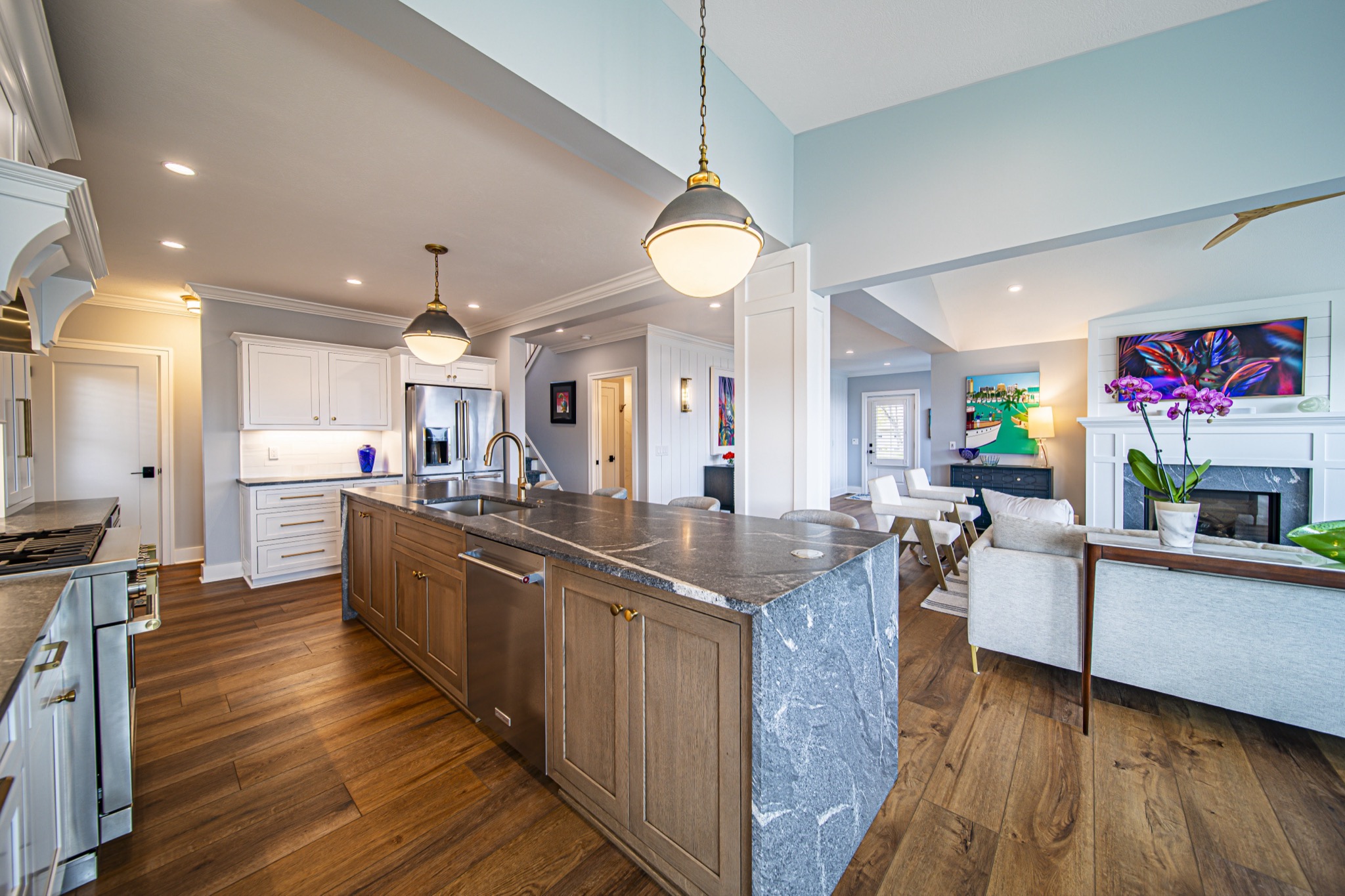 Dark marble waterfall island with walnut base cabinets opening to living room with fireplace — custom kitchen by Skoda Construction, Northeast Ohio