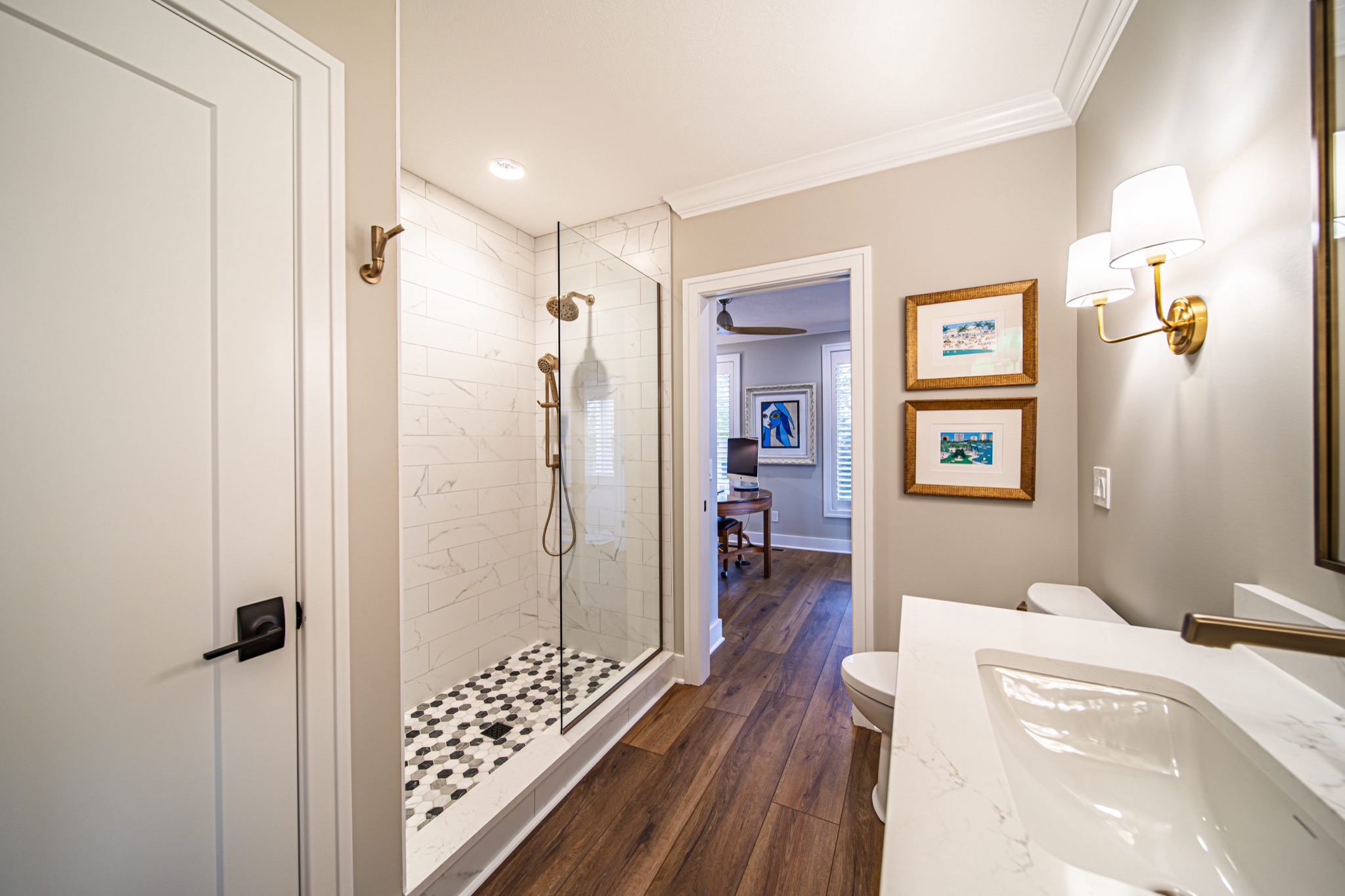 Walk-in shower with marble tile walls, pebble floor, and brass rain showerhead in custom farmhouse — Skoda Construction, Northeast Ohio
