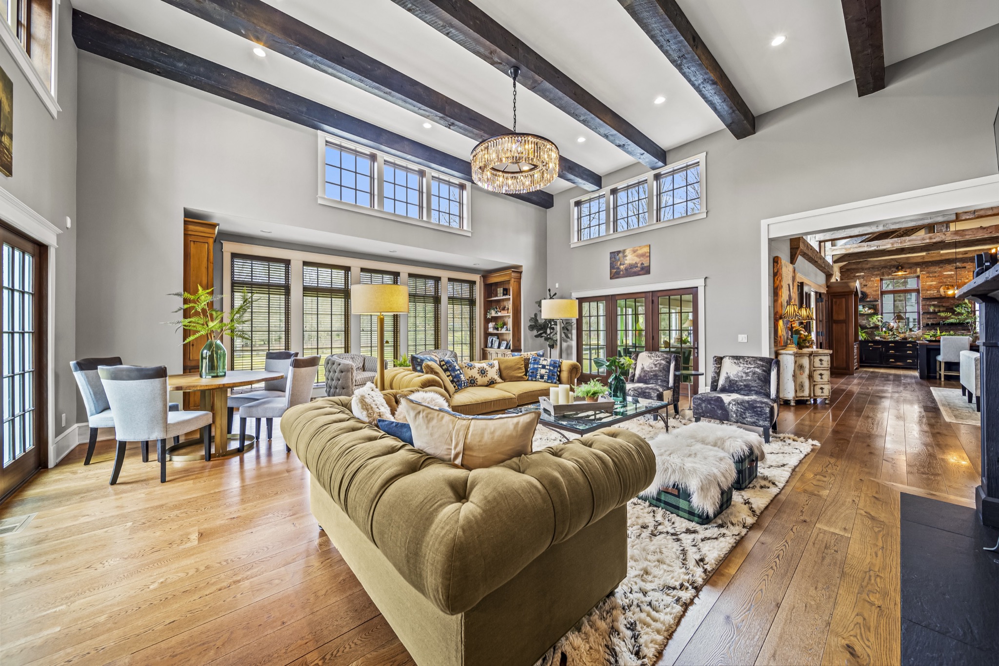 Expansive family room showcasing timber-beamed vaulted ceiling, crystal chandelier, French doors, and curated furnishings — custom estate by Skoda Construction, Northeast Ohio