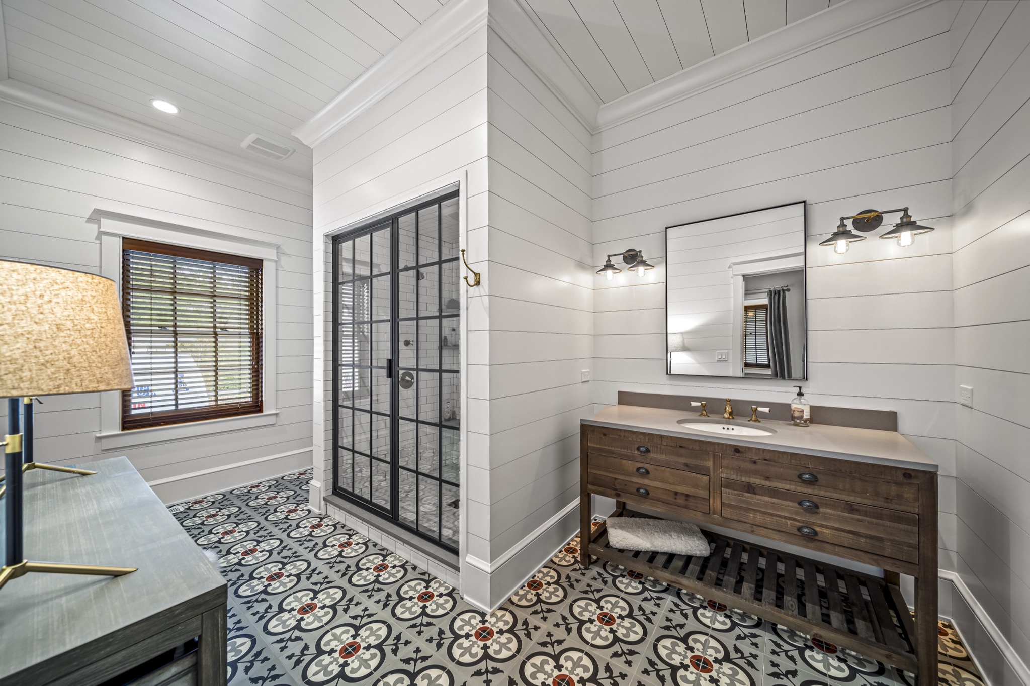 Guest bathroom with hand-painted cement tile floor, industrial glass shower enclosure, shiplap walls, and reclaimed wood vanity — custom home by Skoda Construction, Northeast Ohio