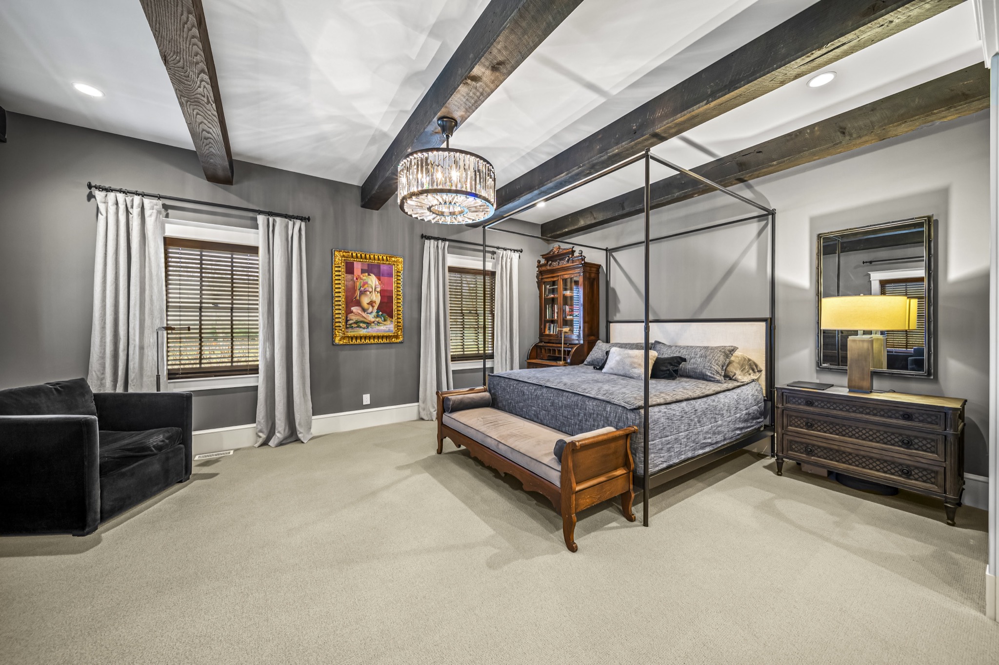 Master bedroom with iron canopy bed, crystal drum chandelier, exposed timber beams, and gray palette — luxury custom home by Skoda Construction, Northeast Ohio
