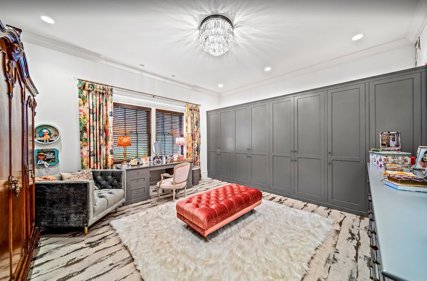 Luxury dressing room with floor-to-ceiling dark gray wardrobe cabinets, crystal flush-mount light, tufted ottoman, and marble floor — custom estate by Skoda Construction, Northeast Ohio