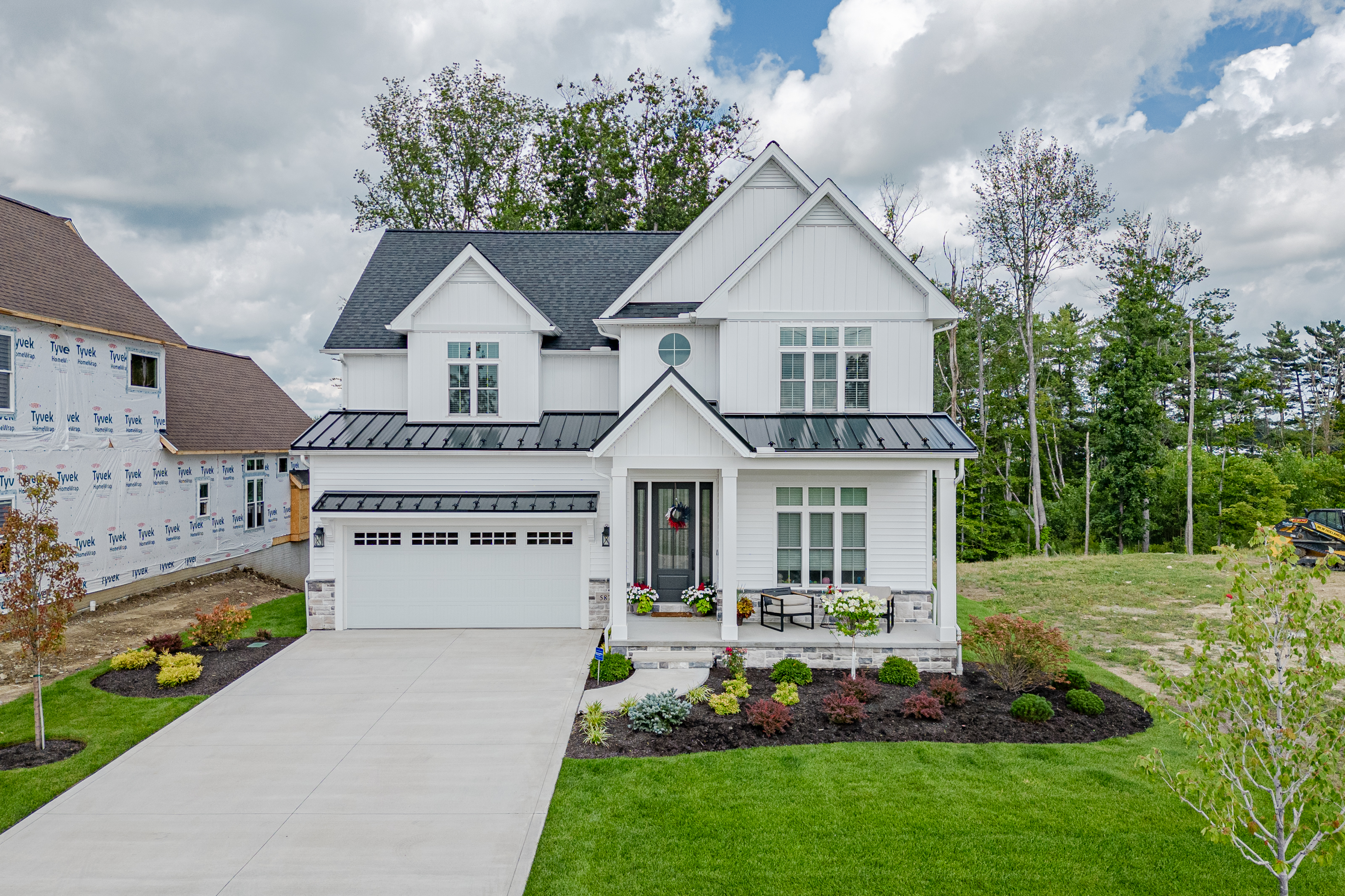 Bright white kitchen with quartz island countertop, pendant lighting, stainless appliances, and hardwood floors — new construction by Skoda Construction, Northeast Ohio