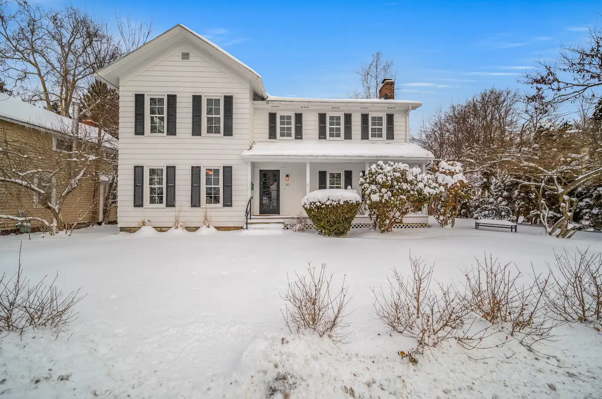 Classic white colonial home with black shutters, front door with sidelight, and snow-covered lawn — whole-home renovation by Skoda Construction, Northeast Ohio